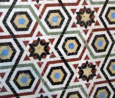 hexagonal floor tile pattern in  red,white, blue,and yellow with six-pointed stars in black