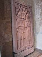 Red sandstone carving of tombstone showing a 14th-century man and woman