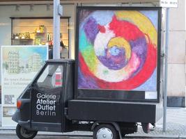 Small truck with advert for Galerie Atelier Outlet; abstract painting of spiral on display