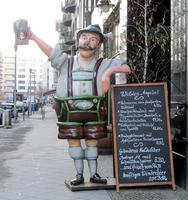 Large statue of man in lederhosen hoisting beer glass; in front of Maximilian's restaurant