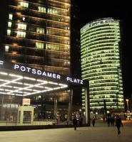 Postdamer Platz train station entrance and curved Deutsche Bahnhof skyscraper at night