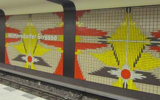 Yellow, orange, and gray mosaic in leaf shape on wall of Wilmersdorfer Strasse subway station