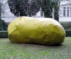 Sculpture that looks like a huge rock wrapped in yellow tape.