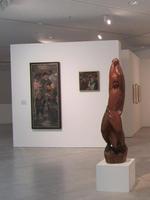 Wooden sculpture of dancing woman in foreground; paintings in background