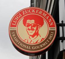 Man with afro and sunglasses on sign: Luigi Zuckermann Traditional Gourmet Deli Since 2009