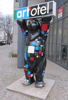 Bear painted in Mondrian colors holding a sign reading “art'otel”