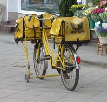 Yellow bicycle with yellow mailbags on front and back