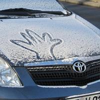 Outline of hand drawn in snow on blue car hood