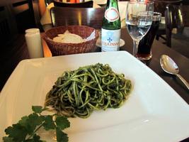Pesto pasta on a plate; water glass in background