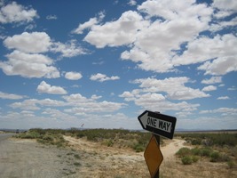 One Way sign with clouds in sky
