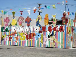 Various cartoon characters on top of fence at “La Piñata Loca” party supply company.