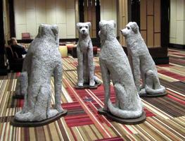 Five large plaster dogs sitting in a circle, on their haunches.