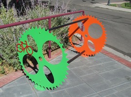 bicycle rack with ends shaped like bike gears, in green and orange