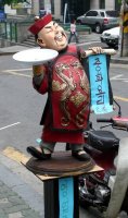 Statue of sterotypical Chinese man in front of restaurant.