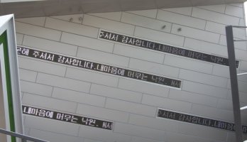 Scrolling signs on wall near down escalator