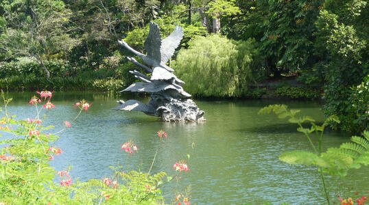 sculpture of flying swans in lake