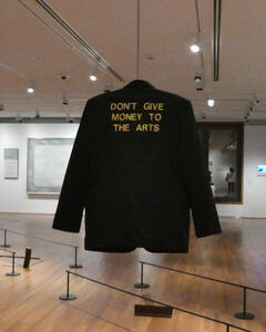 Back of suit jacket with words: Don't give money to the arts