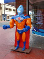 Statue of “person” with orange superhero costume and head shaped like a Viagra pill