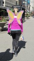 Woman in magenta top and black tights with “butterfly wings” attached to back of shirt.