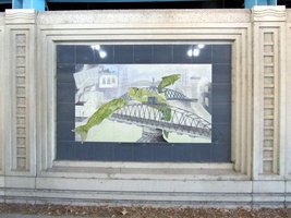 Tile mural on underpass showing green ish leaping over bridges