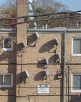 Multiple satellite antennas on side of brick apartment building