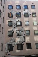Clown-like figures draped around the window frames on exterior of building