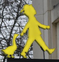 Yellow sign of boy walking with duck behind him
