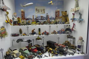 Display case with many toy cars, motorcycles, and airplanes, plus two zeppelins