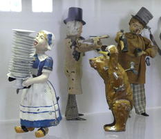 Toy wind-up bear and woman carrying stack of dishes