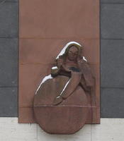Sculpture of woman leaning over a round object (wheel or stone)