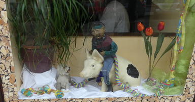 Store window display with man riding on back of pig