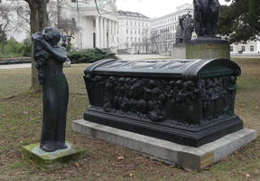 Statue of woman holding dog; next to large coffin