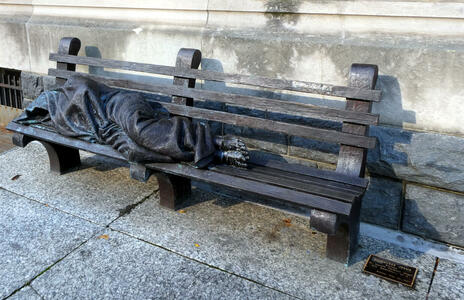Sculpture of Jesus as homeless person asleep on a park bench.