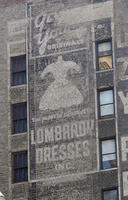 Faded sign for Lombardy Dresses on building brickwork