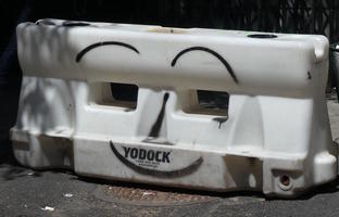 Traffic barrier with eyebrows nose and mouth spraypainted onto it