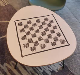 White table with black checkerboard sketched in on it.