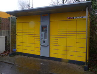 Small yellow outdoor building with automated package storage