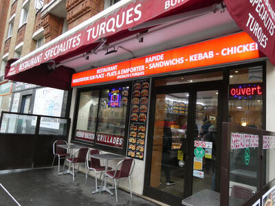 Outside of Restaurant Specialites Turques showing menu and two tables in front.