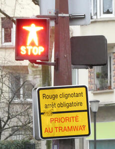 Red light showing man with outstretched arms and word STOP. Sign says “red blinking stop obligatory. Priority to tramway”