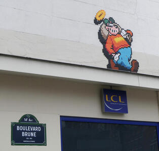 8-bit resolution cartoon character on wall; at bottom of pictureis street sign for Boulevard Brune.