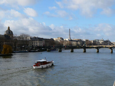 Boat traveling down River Seine; Eiffel Tower in background.