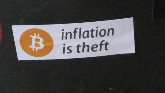 Sticker with bitcoin logo and text “Inflation is theft”