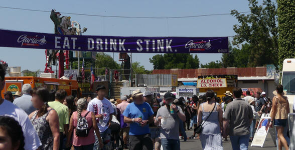 Crowd of people under a banner “Eat. Drink. Stink.”