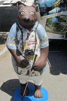 California Bear in shorts, hawaiian shirt, with camera around neck and golf club in hand.
