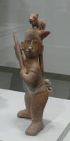 Terra cotta man with small puppy perched on head.