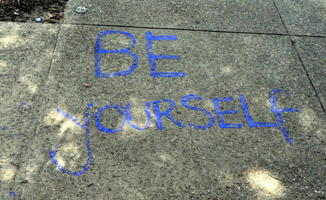“Be yourself” painted in blue on sidewalk