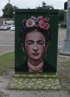 Utility box with painting of Frida Kahlo with flowers in hair and roses painted on base of box
