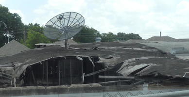 Intact satellite dish on top of badly damaged building