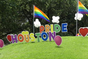 Large cardboard letters “Houston Pride” with rainbow flags on hill lin park