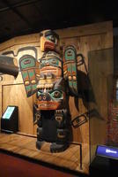 Totem pole with eagle on top and bear-like creature at bottom